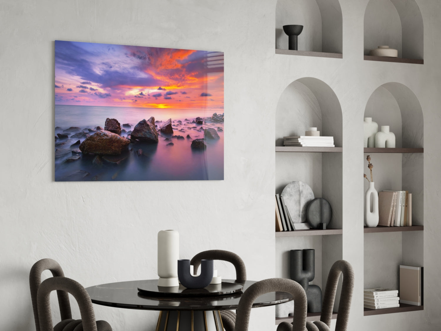 Sunset at Sea glass wall art displayed above a black round dining table with gray chairs in a modern white room with built-in shelving.