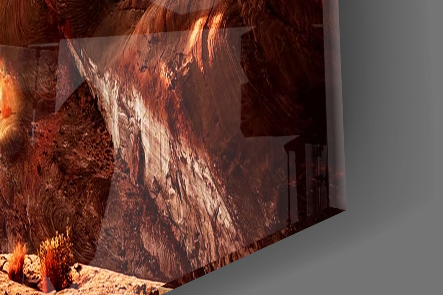Glass wall art panel displaying layered canyon terrain in rust, orange, and cream tones with textured surface details, shown at an angle against gray background.