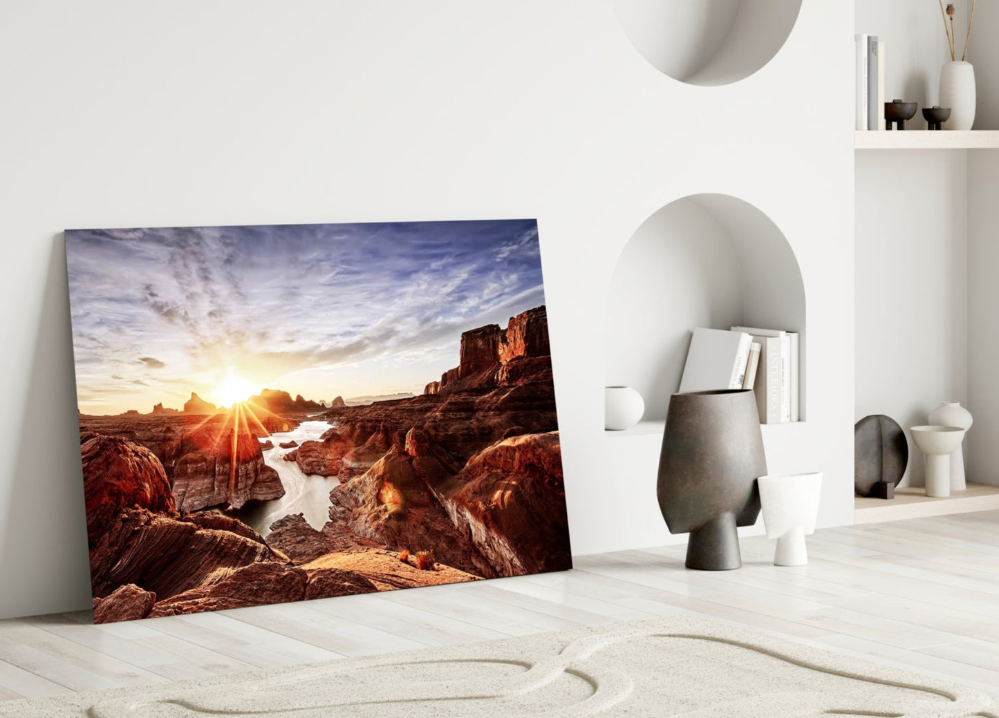 Canyon and Sunset glass wall art leaning against white wall in minimalist interior with sand and decorative objects.