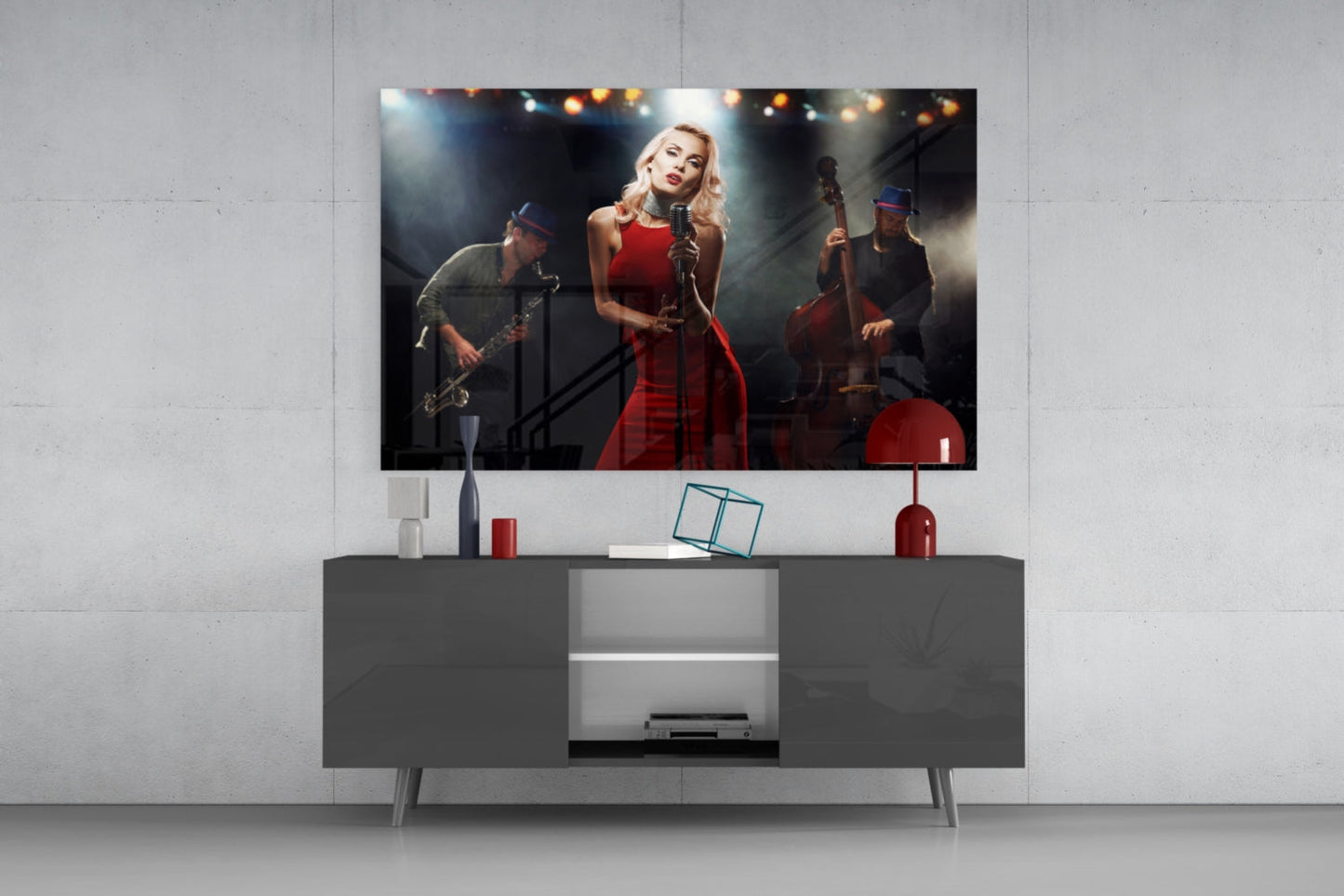 Glass wall art depicting blonde female singer in red dress performing with band members on stage, displayed above gray media console.