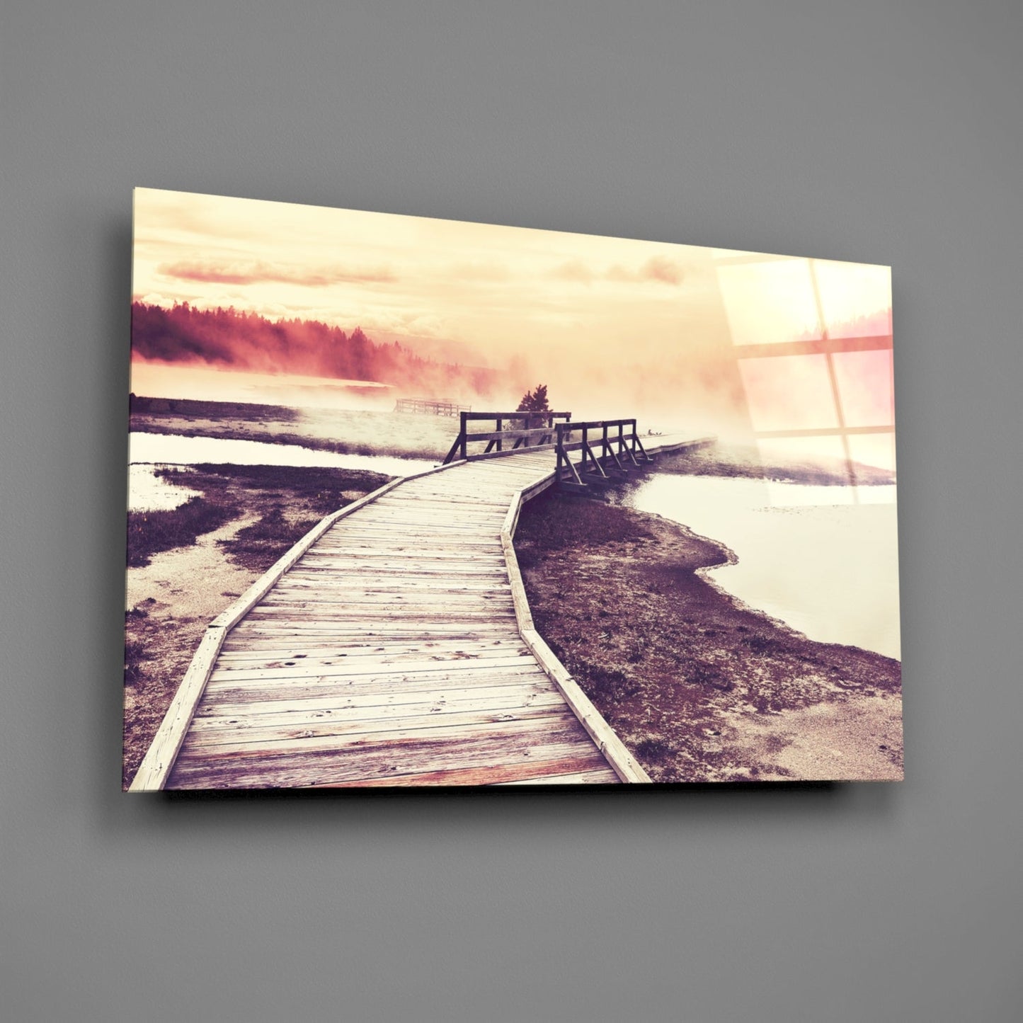 Wooden boardwalk curving toward misty forested shoreline at sunset, displayed as glass wall art with warm sepia tones.