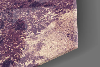 Close-up detail of glass wall art surface showing textured purple and beige tones with grainy finish and subtle brushstroke marks.