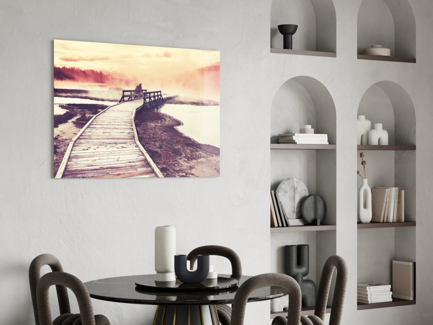 Wooden boardwalk curves toward misty landscape with warm sunset tones displayed as glass wall art above dining table.