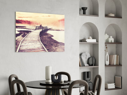 Wooden boardwalk curves toward misty landscape with warm sunset tones displayed as glass wall art above dining table.