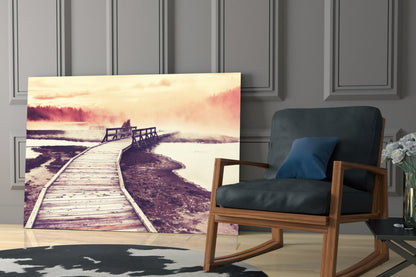 Glass wall art depicting a wooden boardwalk extending toward misty mountains and water, displayed in a modern living room interior.