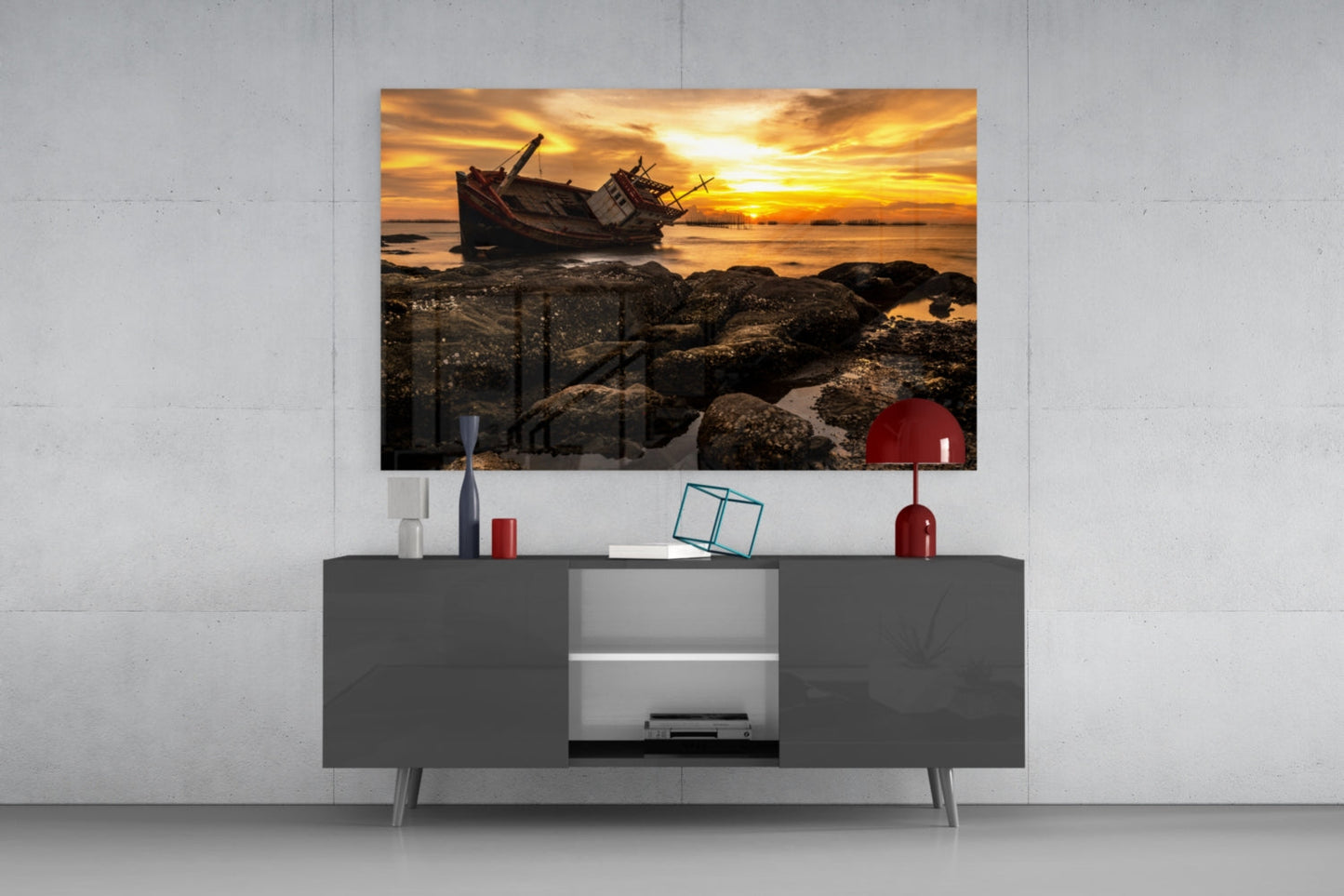 Shipwreck glass wall art displayed above gray media console, showing golden sunset with abandoned boat and rocky shoreline.