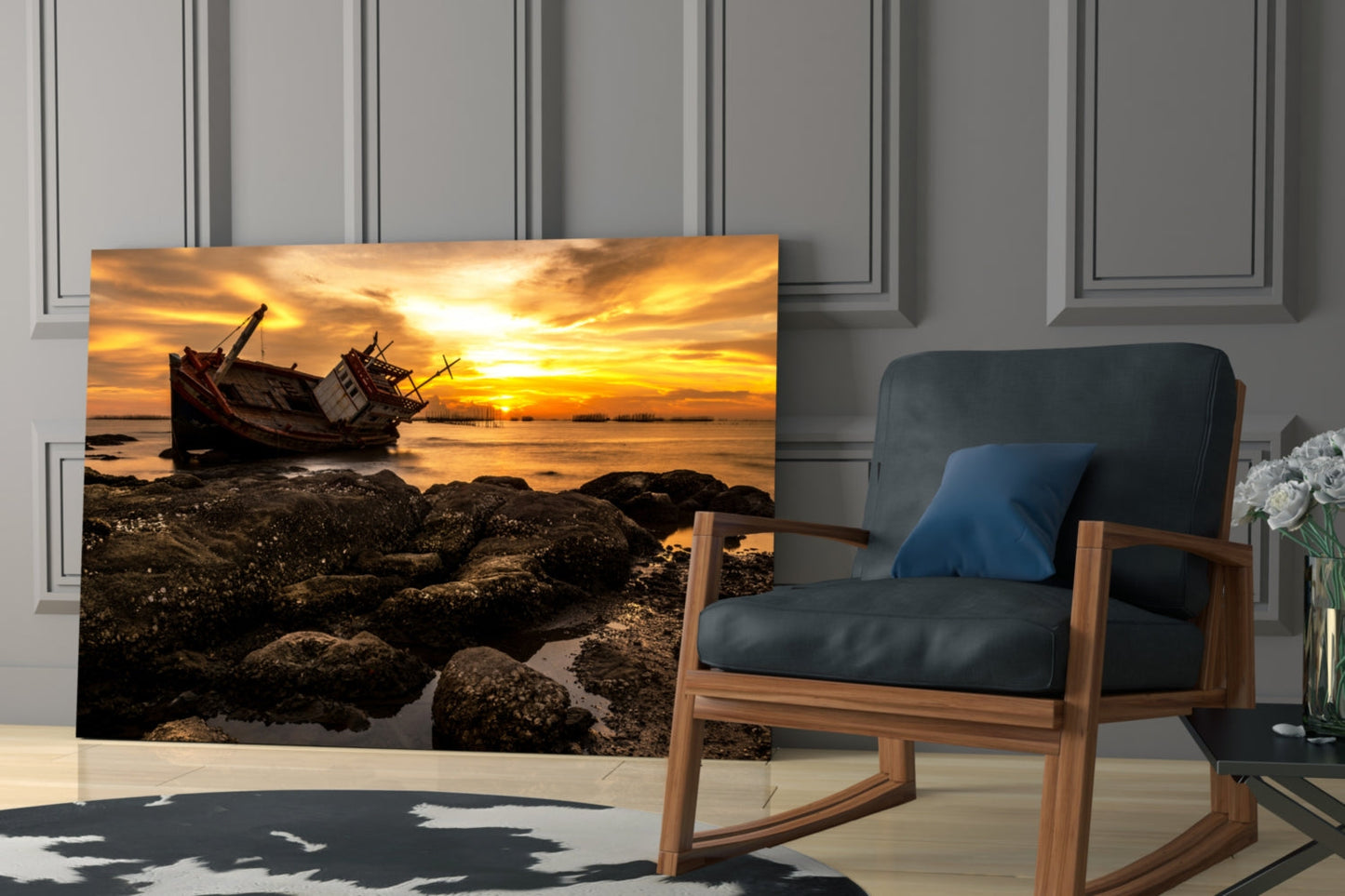 Shipwreck glass wall art displayed in modern living room beside wooden chair, showing golden sunset over tilted ship and rocky shore.