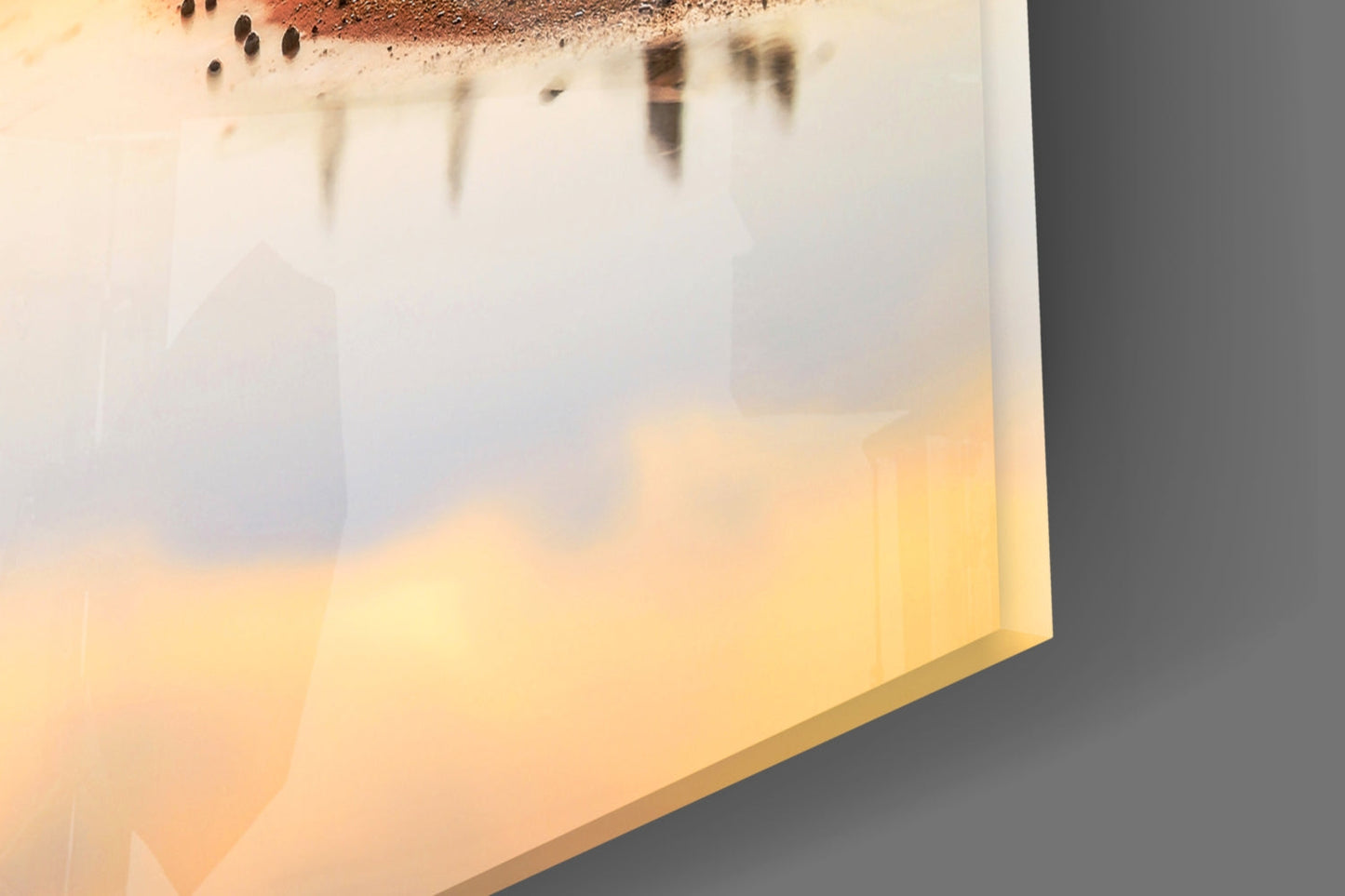 Close-up of glass wall art showing layered yellow and cream tones with textured brown top edge detail.
