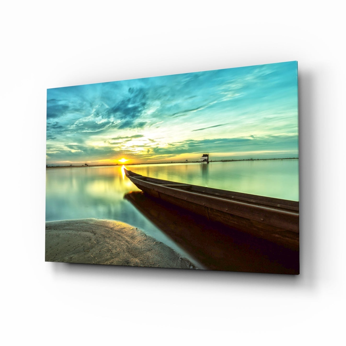 Dark wooden kayak beached in foreground with serene sunset reflection on calm turquoise water and distant pier.