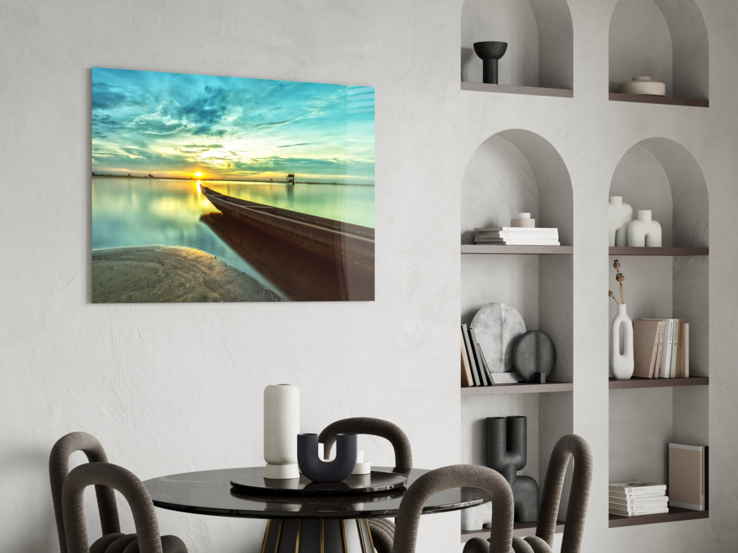Glass wall art print displayed above a black round dining table showing a wooden kayak beached at sunset with turquoise water and golden sky.