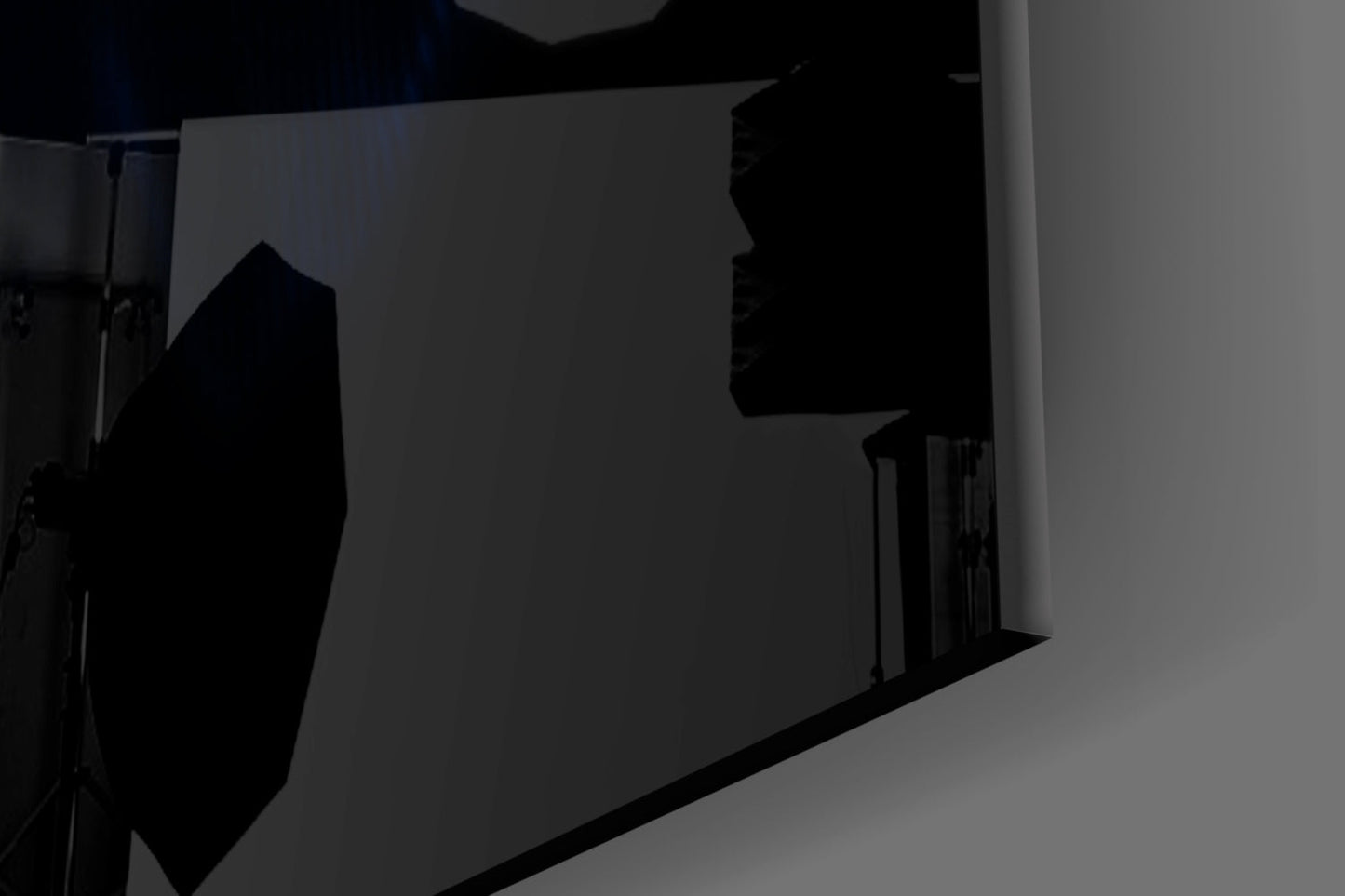 Silhouetted view of frosted glass wall panel mounted in corner with studio lighting creating shadow effects on gray background.
