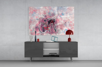 Red bicycle with watercolor splashes displayed on glass wall art above dark media console with red lamp and accessories.