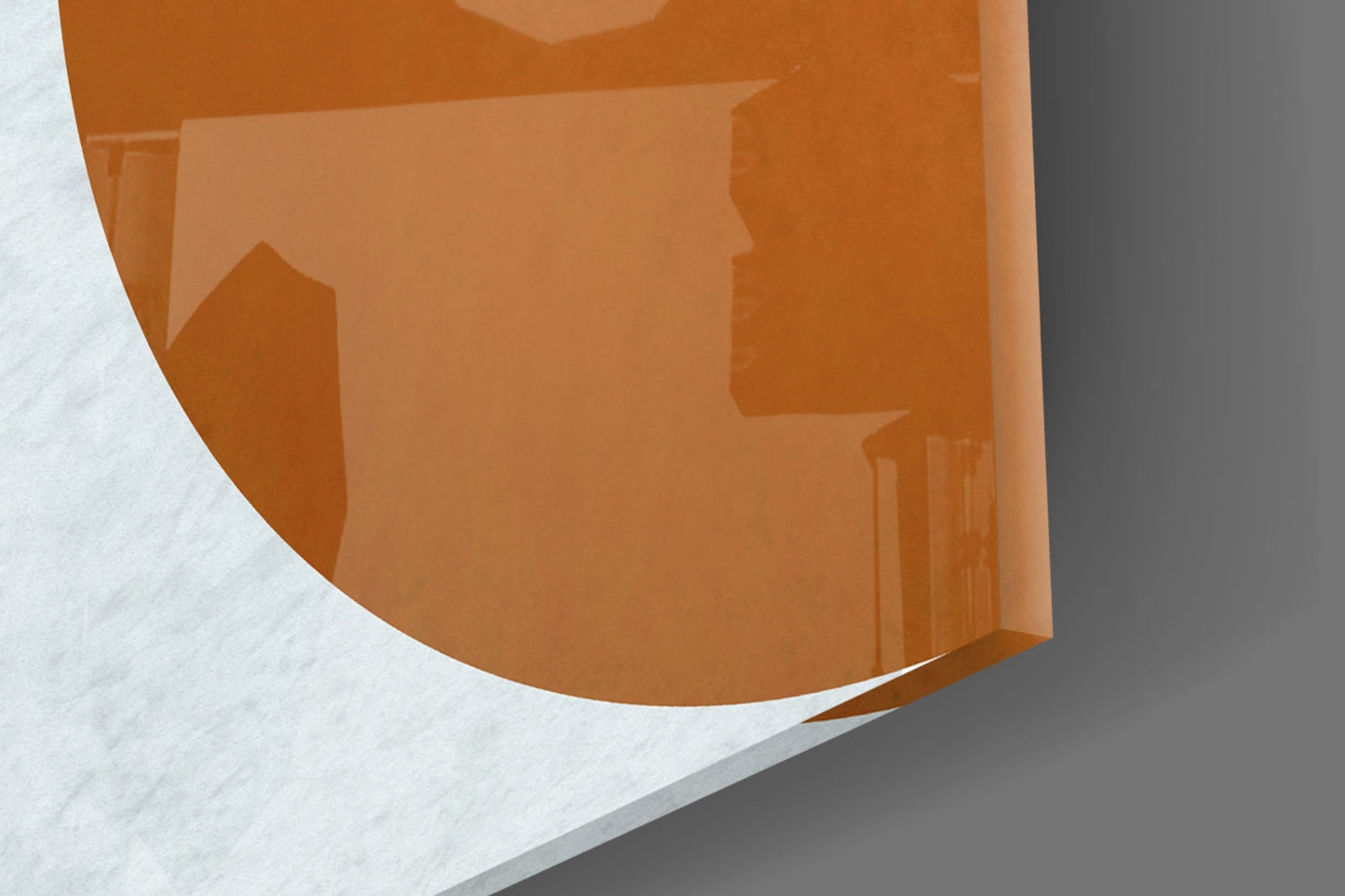 Close-up angled view of amber glass wall art panel showing translucent orange surface with interior architectural shadows and white background.