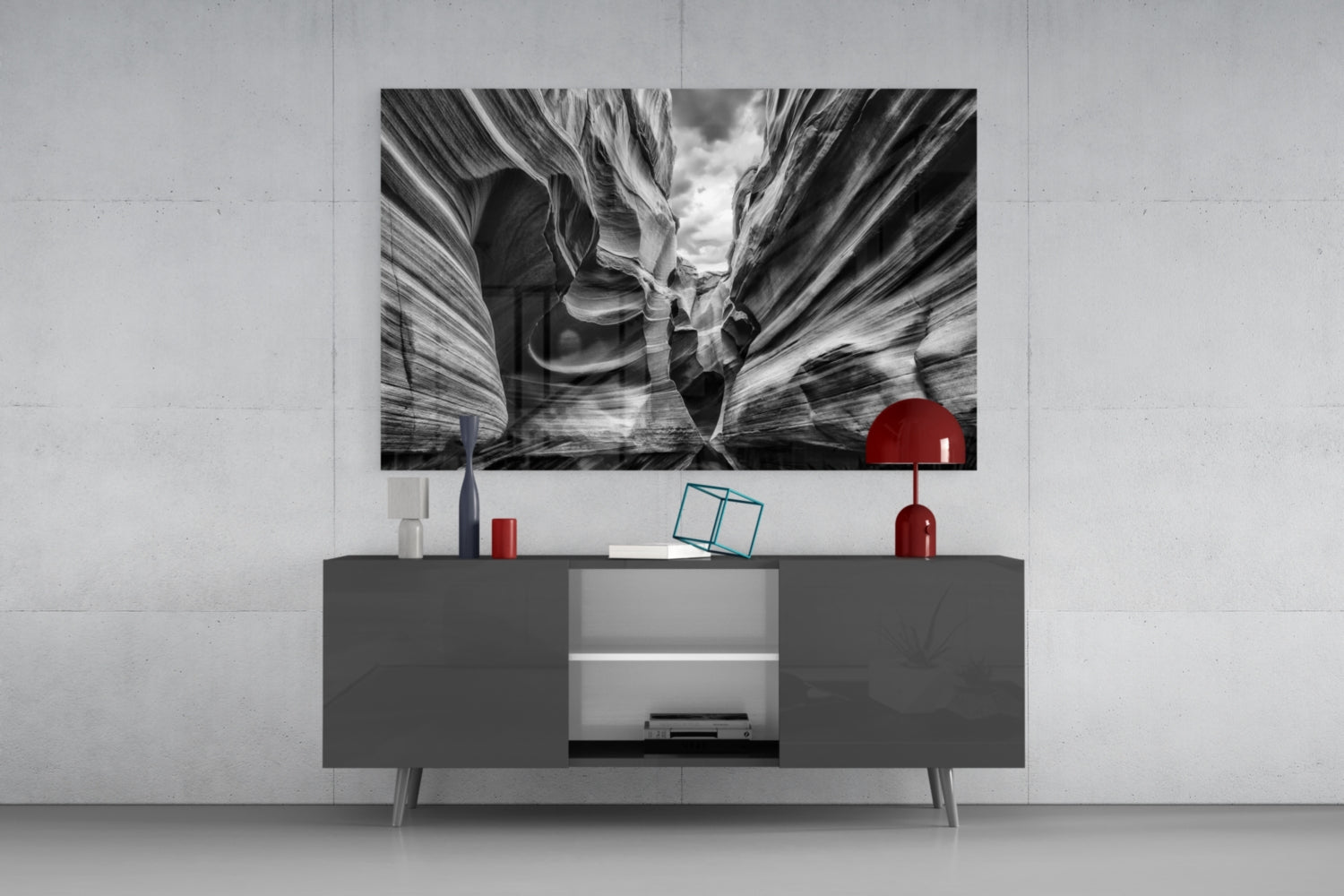 Black and white Grand Canyon glass wall art displaying layered canyon formations displayed above a dark media console with red decorative accessories.