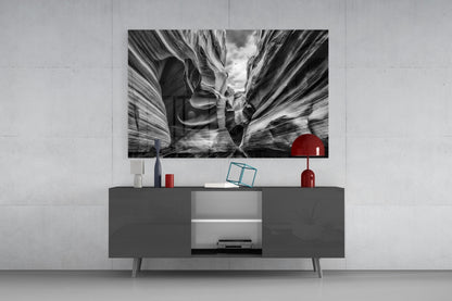 Black and white Grand Canyon glass wall art displaying layered canyon formations displayed above a dark media console with red decorative accessories.