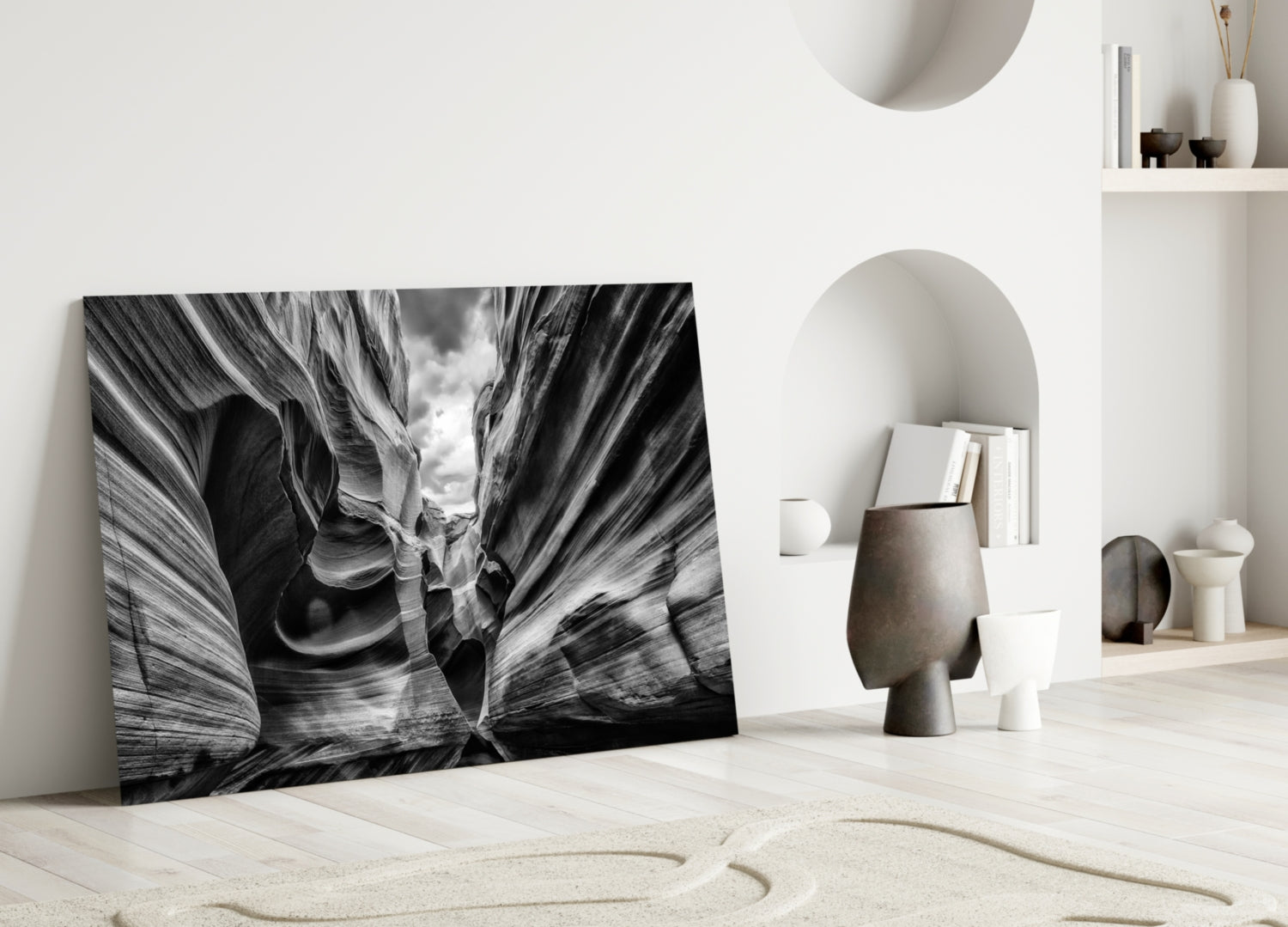 Black and white glass wall art leaning against white wall displays dramatic canyon rock formations with layered striations.