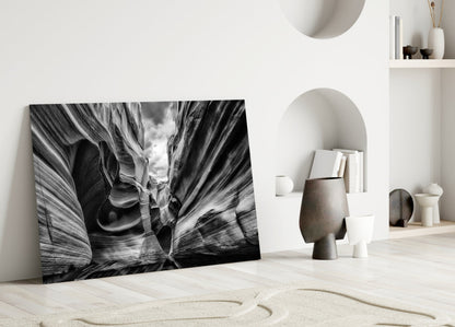 Black and white glass wall art leaning against white wall displays dramatic canyon rock formations with layered striations.
