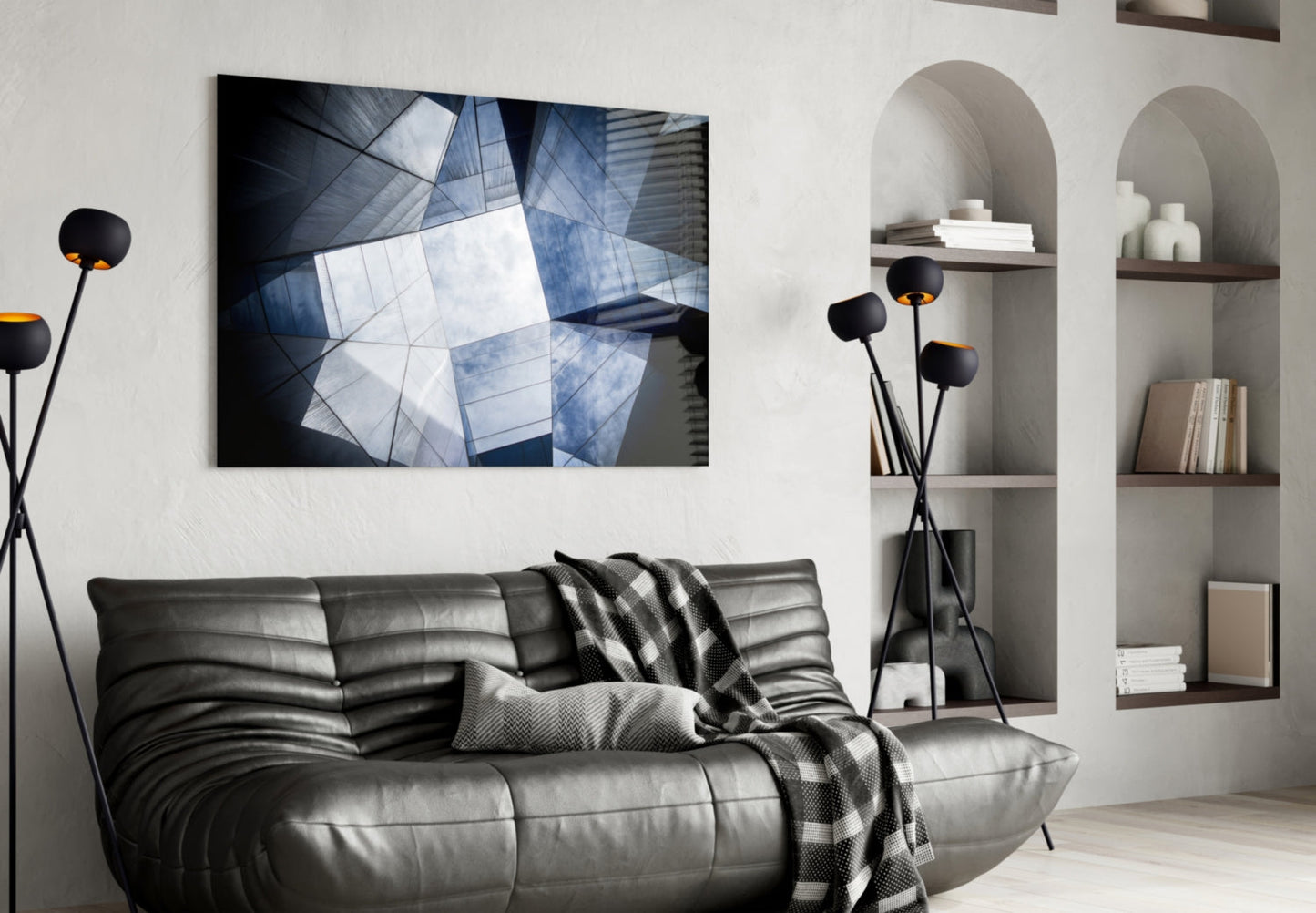 Modern living room with black leather sofa displaying horizontal rectangular artwork of blue and white geometric glass building facade above it.
