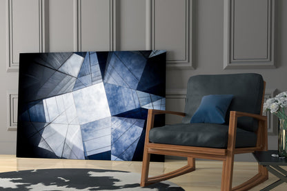 Modern living room with geometric glass wall art displaying blue and white angular patterns displayed next to mid-century wooden chair.