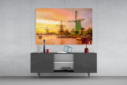 Windmills glass wall art with warm sunset tones hung above modern dark gray media console in minimalist room setting.