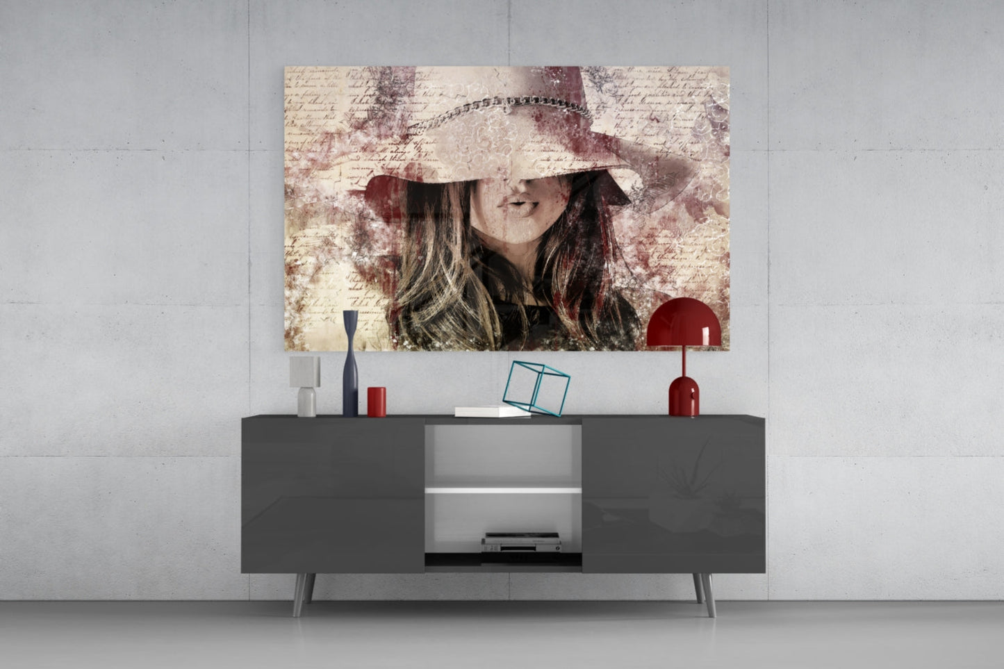 Vintage-style glass wall art of a woman wearing a wide-brimmed hat displayed above a dark gray media console with decorative accessories.