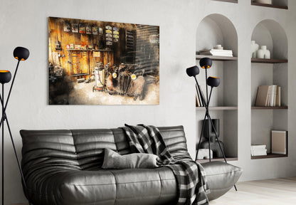 Black leather sofa with striped throw blanket against white wall displaying framed vintage garage photograph above.