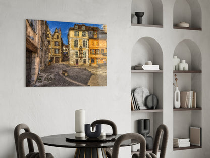 Medieval Square Glass Wall Art displayed above a round black dining table, showing a European stone courtyard with yellow and tan buildings under blue sky.