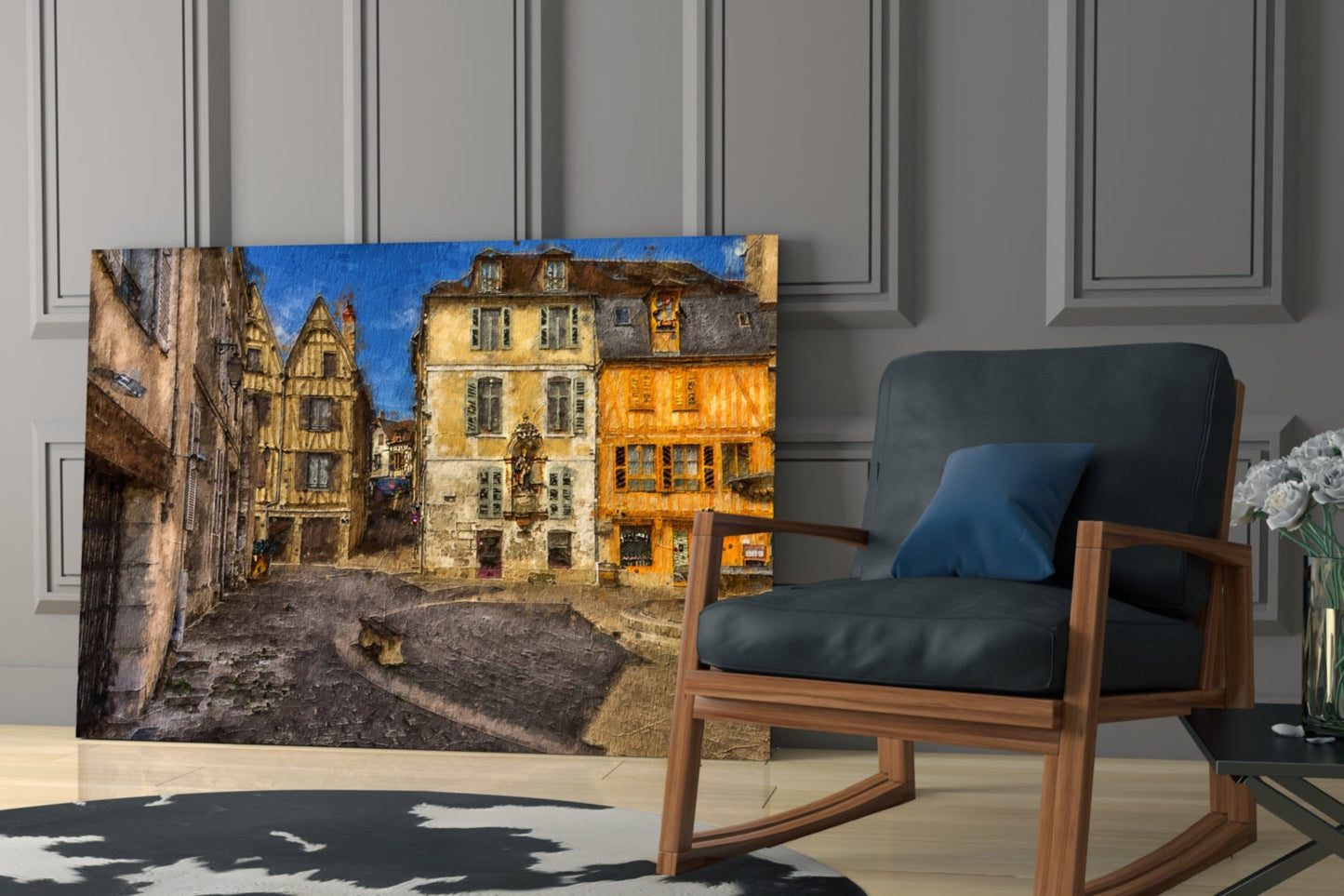 Glass wall art depicting a medieval European street scene with colorful buildings in yellow and orange tones, displayed in a modern living room setting.