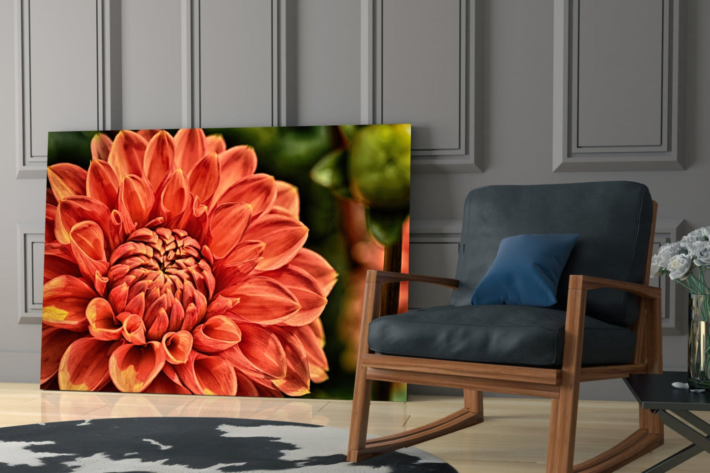 Orange Gerbera glass wall art displayed in a modern living room beside a wooden rocking chair with dark cushions.