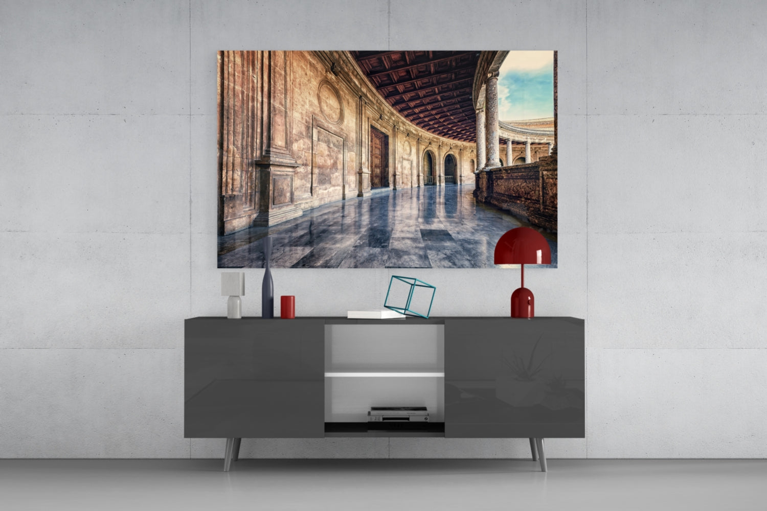 Baroque Building Glass Wall Art depicting a sunlit classical colonnade displayed above a dark gray media console with red decorative accessories.