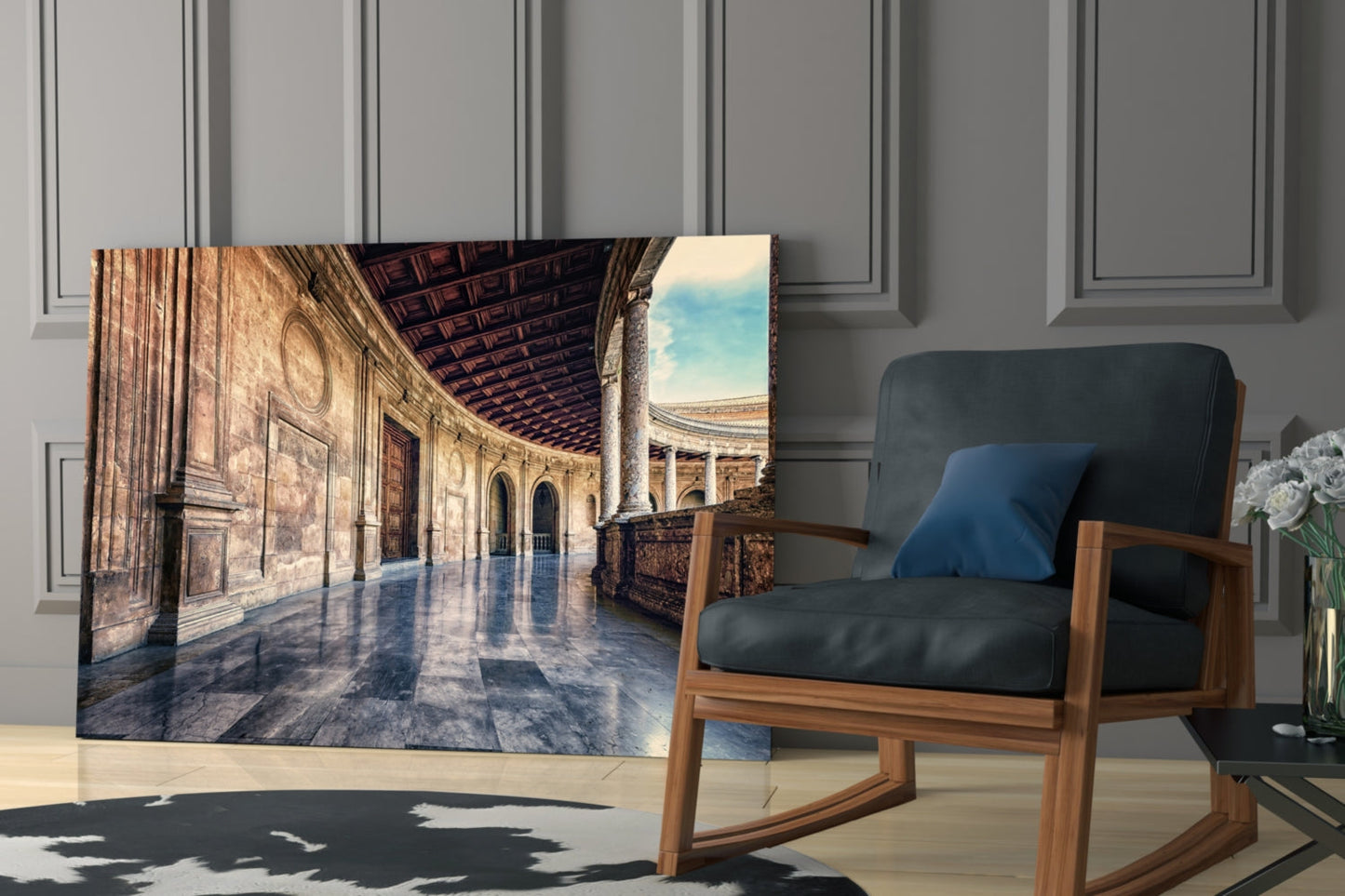 Glass wall art displaying a sunlit baroque colonnade with ornate architecture and reflective marble floors, displayed in a modern living room next to a wooden chair.