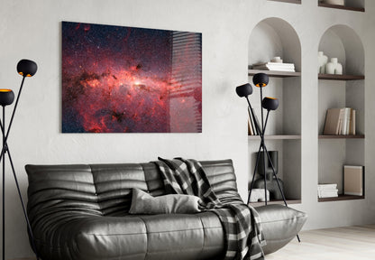Red and pink galactic nebula glass wall art hanging above black leather sofa in modern living room with shelving.