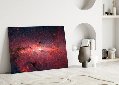 Red Nebula Glass Wall Art leaning against white wall in minimalist room with sand floor and decorative objects.