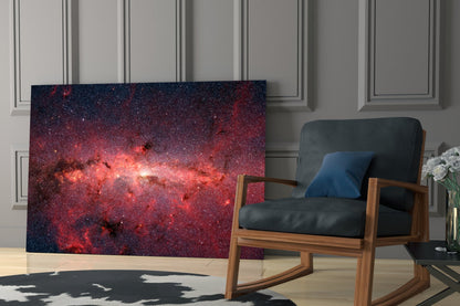 Red Nebula Glass Wall Art displayed in modern living room with wooden chair, black leather cushions, and paneled white wall backdrop.