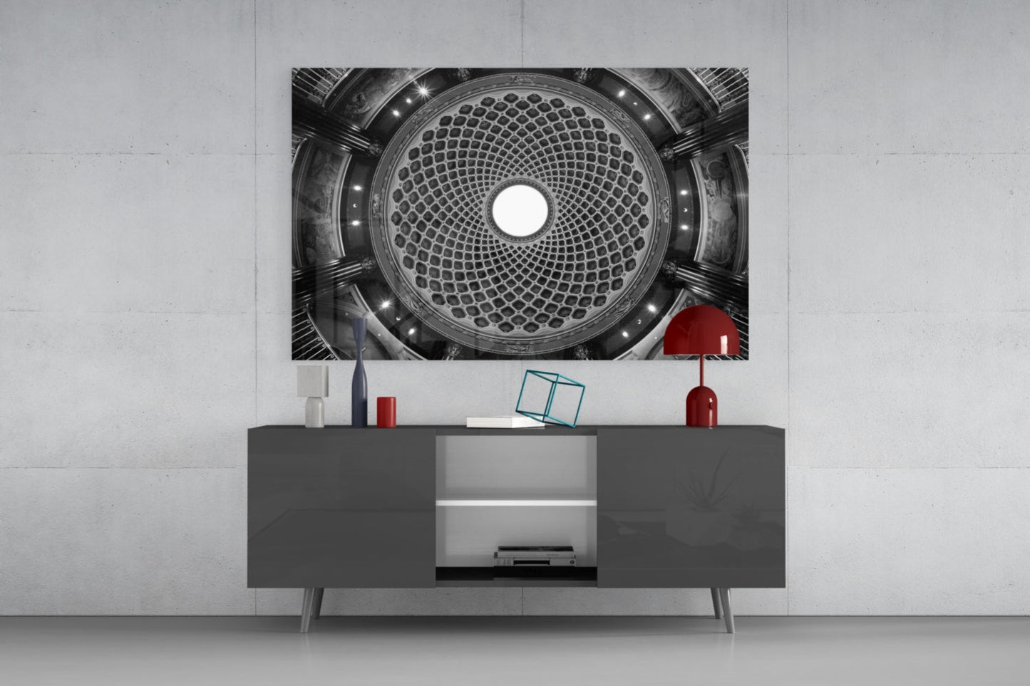 Black and white photograph of ornate domed ceiling with geometric pattern displayed above dark media console with red decorative accessories.