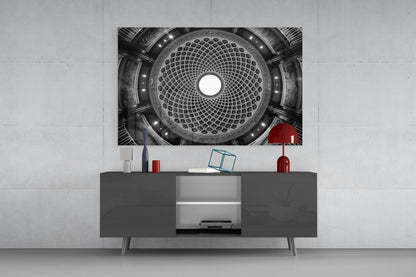Black and white photograph of ornate domed ceiling with geometric pattern displayed above dark media console with red decorative accessories.