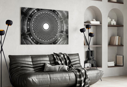 Black and white photograph of a domed architectural ceiling with geometric pattern and central light, displayed above a black leather sofa in a modern interior.