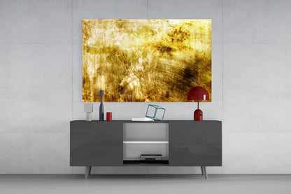 Gold textured abstract glass artwork displayed above dark gray media console with red decorative accessories in modern living room setting.