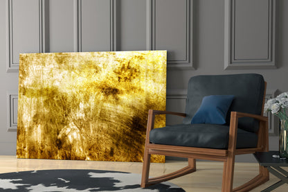 Yellow and gold abstract textured glass wall art installed in modern living room beside wood-framed chair with black upholstery.