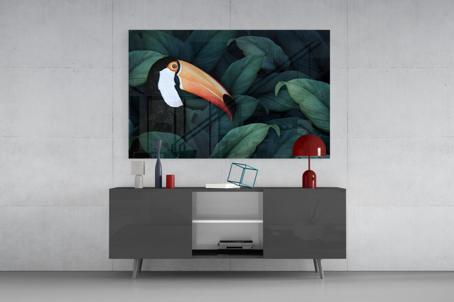 Toucan glass wall art displayed above a dark grey media console in a modern living room setting with decorative accessories.