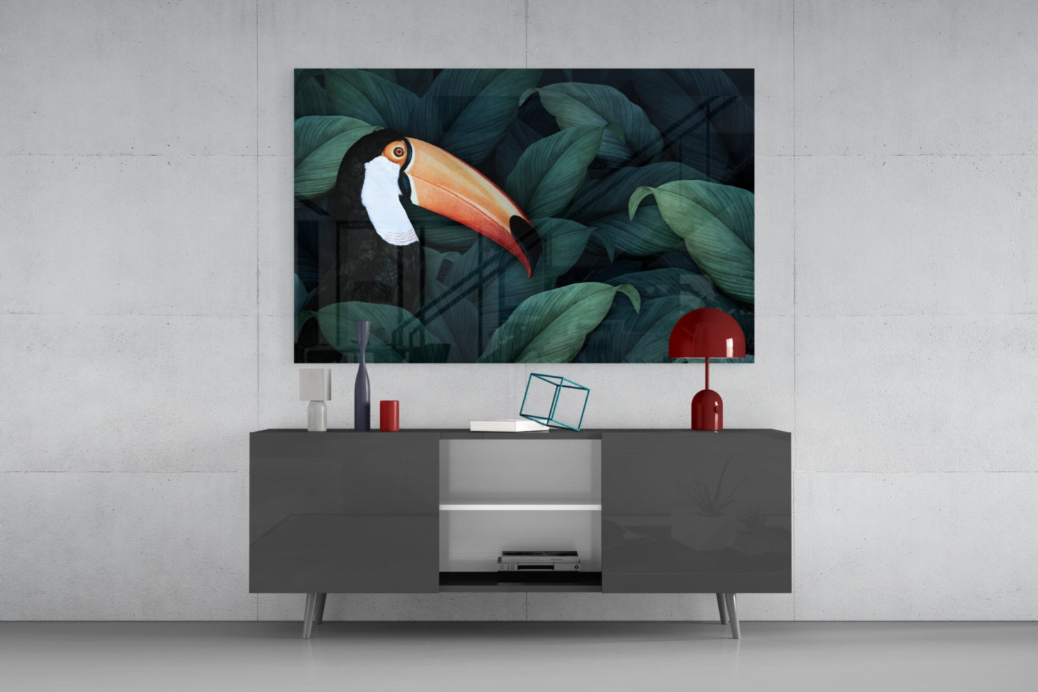 Toucan glass wall art displayed above a dark grey media console in a modern living room setting with decorative accessories.