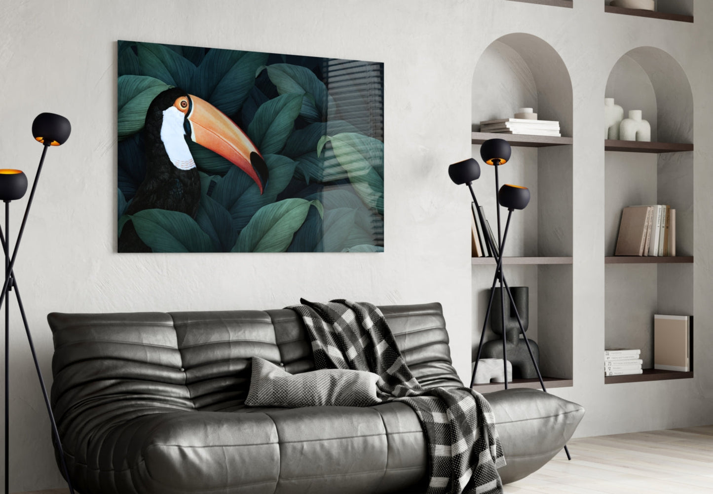 Toucan glass wall art hanging above gray leather sofa in modern living room with built-in shelving and black floor lamp.