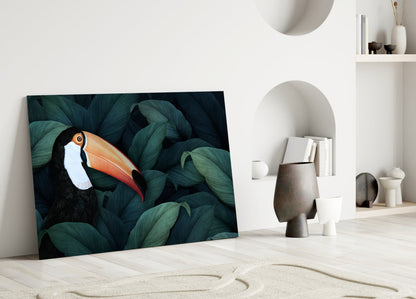 Toucan glass wall art leaning against white wall in minimalist interior with decorative objects and shelving.