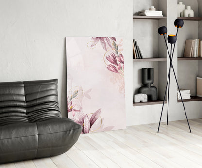 Pink floral glass wall art displayed leaning against white wall in modern living room with black leather chair and shelving.
