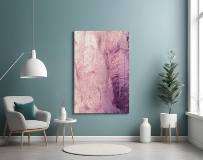 Pink and purple abstract watercolor glass wall art displayed in a minimalist teal room with white furniture and plants.