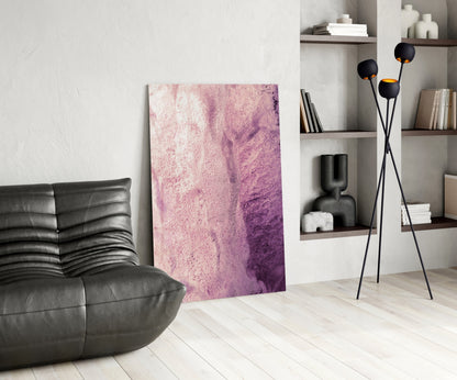 Pink and purple abstract textured glass art panel displayed in modern living room with black leather chair and shelving unit.