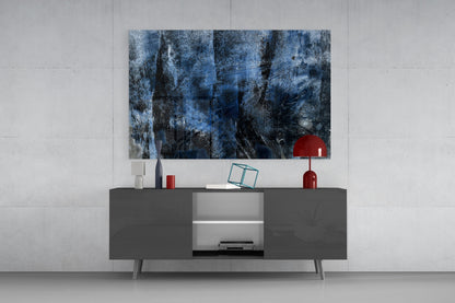 Blue abstract glass wall art with dark weathered texture displayed above dark gray media console in modern living room setting.