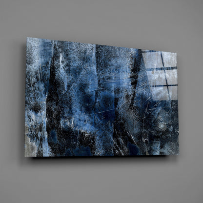 Angled view of blue abstract glass wall art with layered textured patterns, dark veining, and light horizontal streaks against gray background.