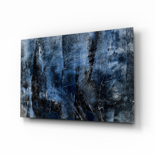 Angled perspective view of blue abstract glass wall art with dark mottled textures and white scratched lines against weathered surface.