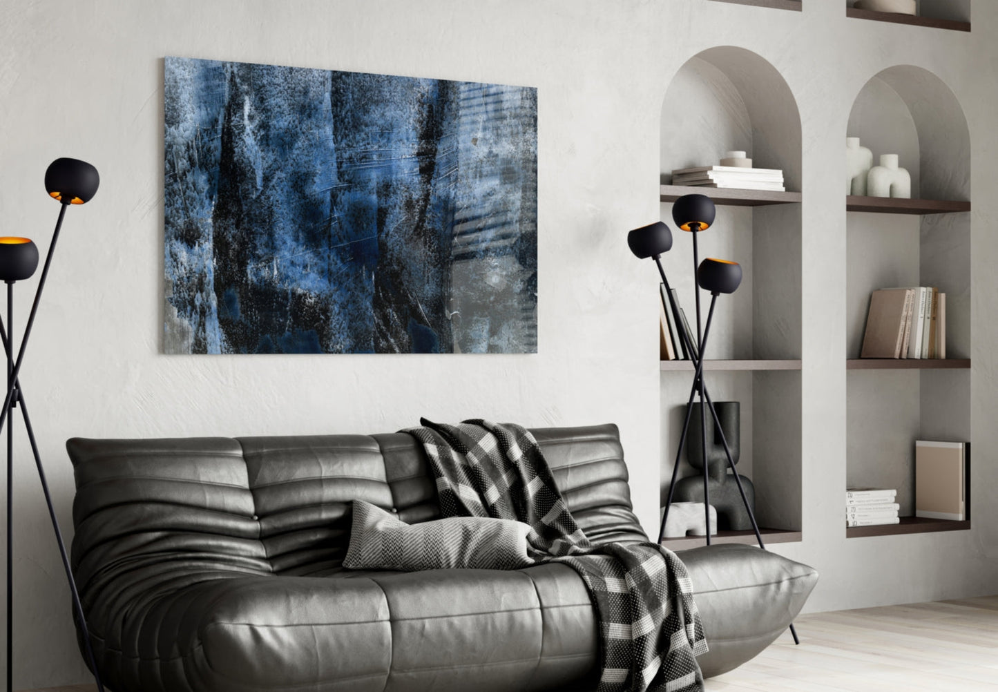Blue abstract glass wall art with textured layers hung above black leather sofa in modern living room.